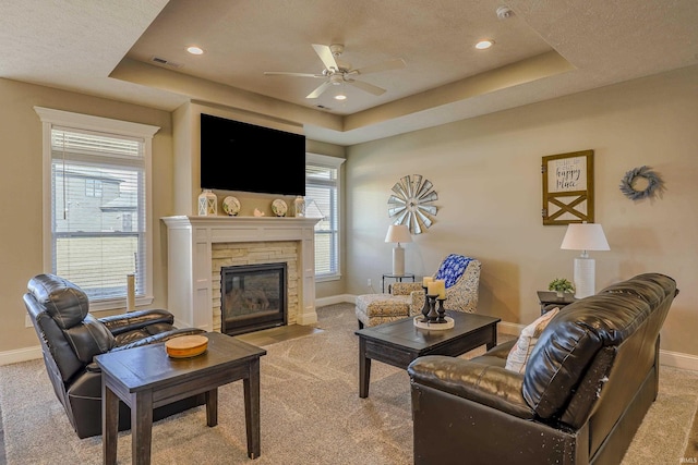 living area with a raised ceiling, baseboards, and light carpet