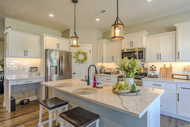 kitchen featuring visible vents, appliances with stainless steel finishes, white cabinetry, and wood finished floors