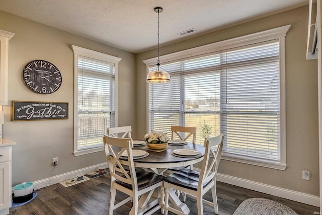 dining space with baseboards, a textured ceiling, and dark wood-style floors