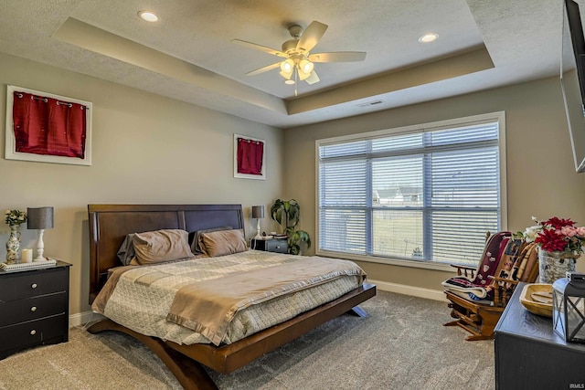 bedroom with a raised ceiling, visible vents, baseboards, and carpet floors