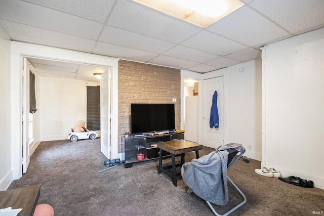 carpeted living room featuring a paneled ceiling and baseboards