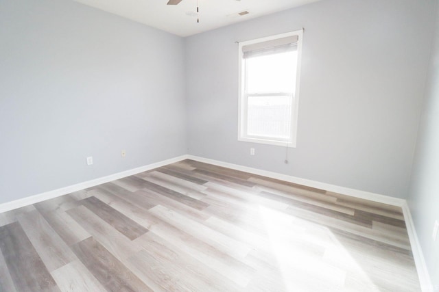 spare room featuring light wood-type flooring, visible vents, baseboards, and ceiling fan