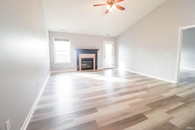 unfurnished living room with light wood-style flooring, a tile fireplace, and baseboards