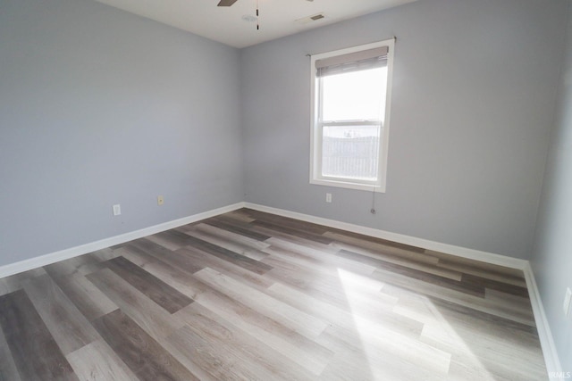 spare room with visible vents, baseboards, wood finished floors, and a ceiling fan