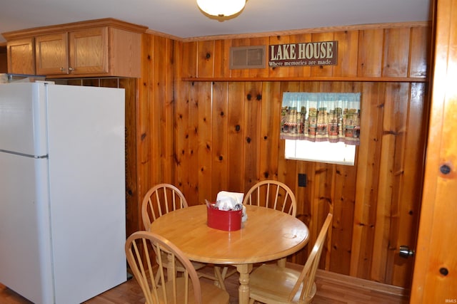 dining space featuring visible vents, wood finished floors, and wood walls