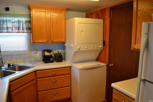 laundry area featuring stacked washer and clothes dryer and a sink