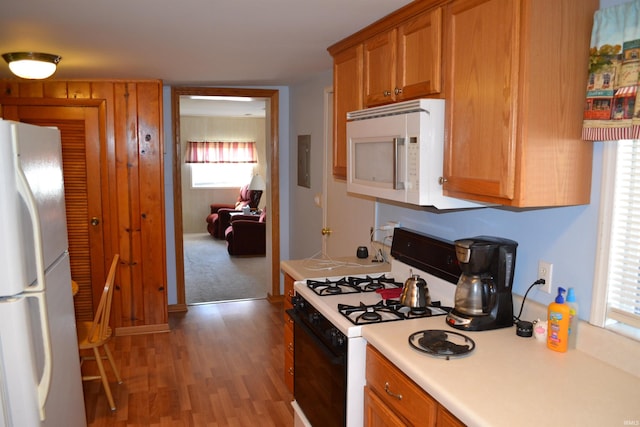 kitchen with white appliances, light wood-style floors, brown cabinetry, and light countertops