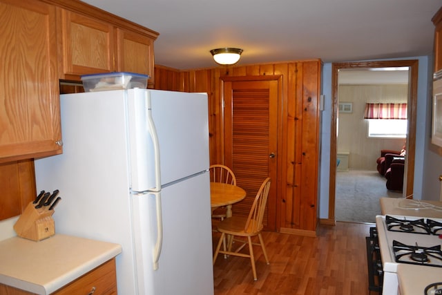 kitchen with white appliances, light wood-style flooring, brown cabinetry, and light countertops