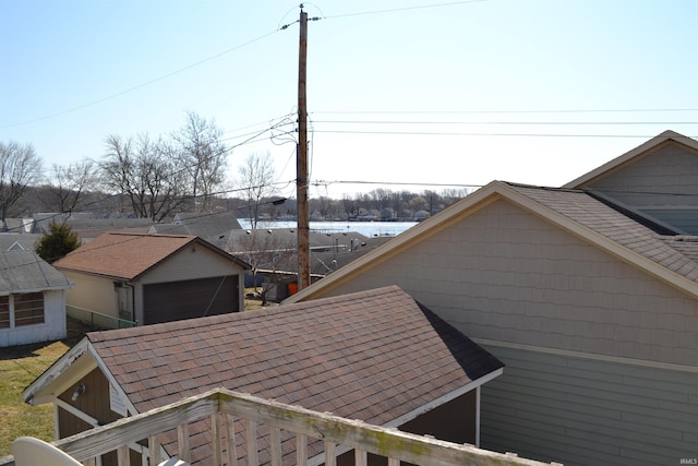 view of side of property with a detached garage, an outbuilding, and a shingled roof