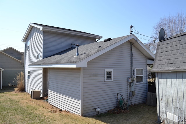 back of house with a yard and a shingled roof