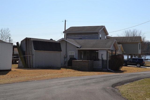 view of front of property featuring a storage unit, an outdoor structure, and a shingled roof