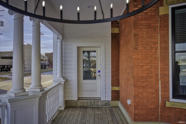 view of exterior entry with a porch and brick siding