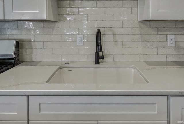 kitchen with white cabinets, light stone countertops, and a sink