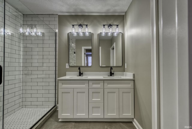 bathroom featuring a textured ceiling, a shower stall, double vanity, and a sink