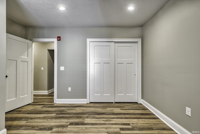 unfurnished bedroom featuring recessed lighting, baseboards, and dark wood-style flooring