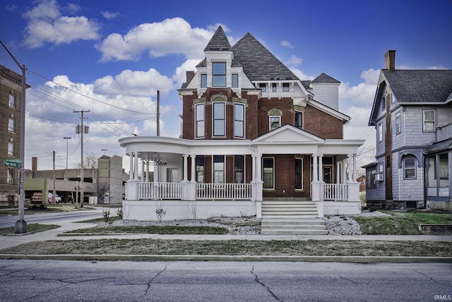 victorian-style house featuring brick siding and covered porch