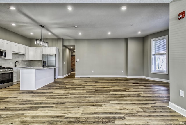 kitchen with dark wood finished floors, open floor plan, decorative backsplash, appliances with stainless steel finishes, and a sink