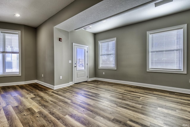 entrance foyer featuring a textured ceiling, baseboards, and wood finished floors