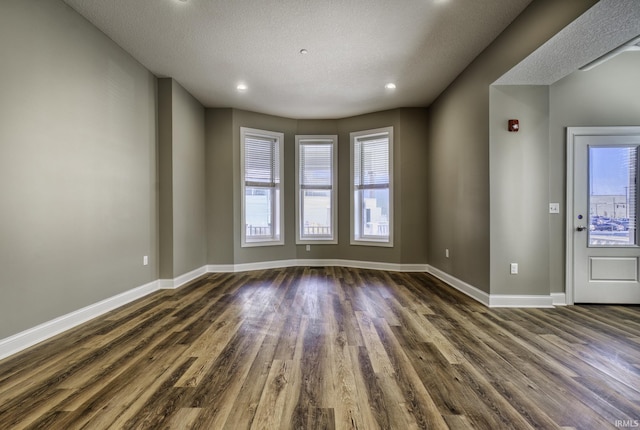 spare room featuring a wealth of natural light, baseboards, and wood finished floors