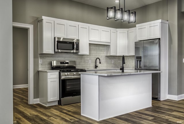 kitchen with appliances with stainless steel finishes, white cabinets, light countertops, decorative backsplash, and dark wood-style flooring