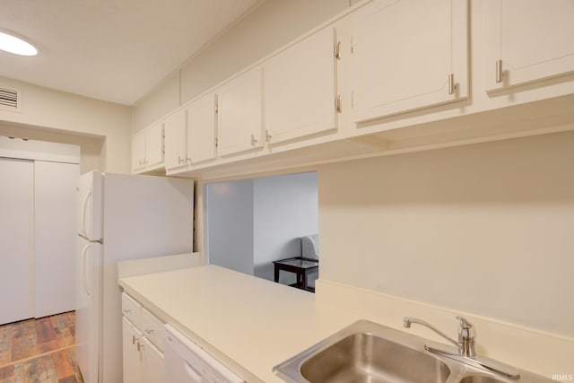 kitchen featuring white appliances, white cabinetry, light countertops, and a sink