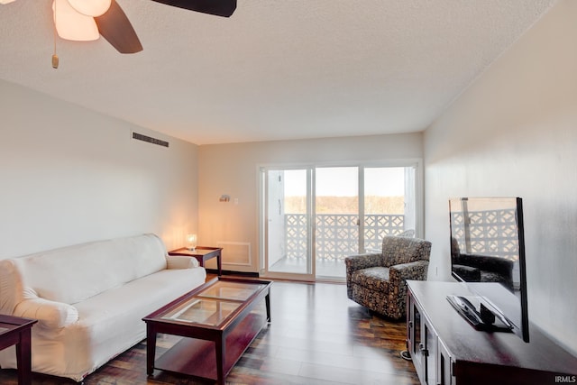 living area with visible vents, a textured ceiling, dark wood-type flooring, and ceiling fan