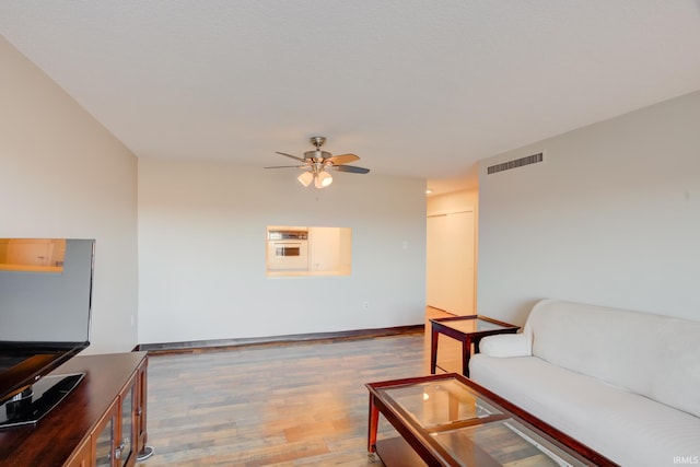 living room featuring baseboards, wood finished floors, visible vents, and ceiling fan