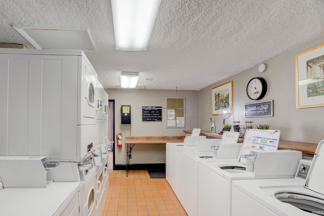 community laundry room with light tile patterned floors, a textured ceiling, stacked washer and clothes dryer, and washing machine and dryer