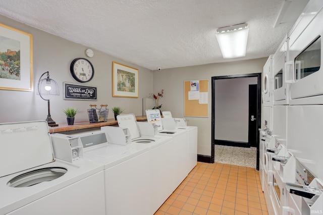 shared laundry area with stacked washer / dryer, a textured ceiling, light tile patterned floors, and washer and clothes dryer