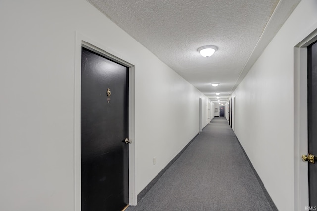 hall featuring baseboards, carpet floors, and a textured ceiling