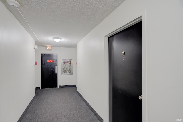 hallway featuring elevator, baseboards, carpet floors, and a textured ceiling