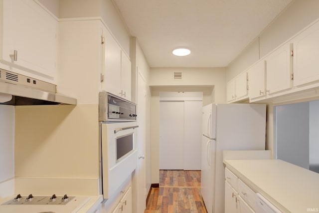 kitchen featuring visible vents, under cabinet range hood, wood finished floors, white cabinetry, and white appliances