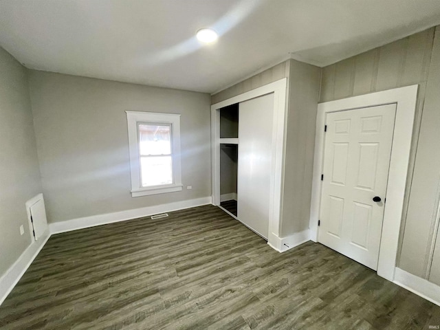 unfurnished bedroom featuring visible vents, baseboards, a closet, and dark wood-style flooring