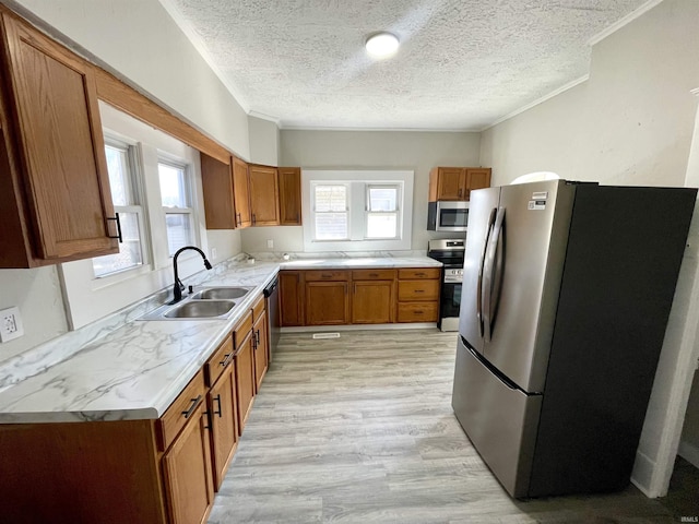 kitchen featuring a sink, ornamental molding, brown cabinetry, and stainless steel appliances