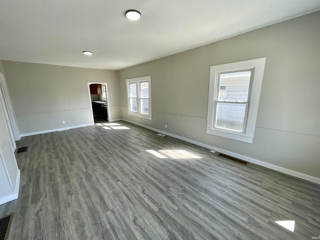 unfurnished living room featuring visible vents, baseboards, and wood finished floors