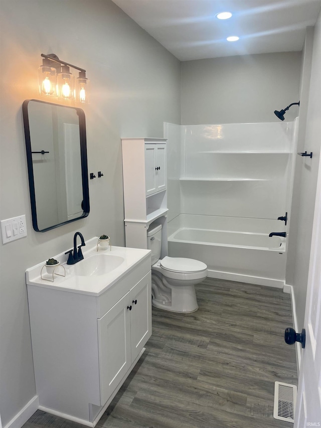 bathroom featuring vanity, washtub / shower combination, wood finished floors, visible vents, and toilet