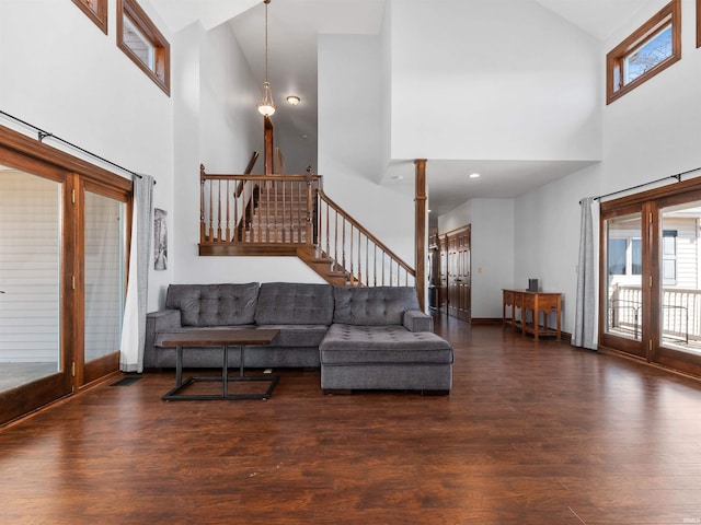 living room with a healthy amount of sunlight, wood finished floors, stairs, and ornate columns