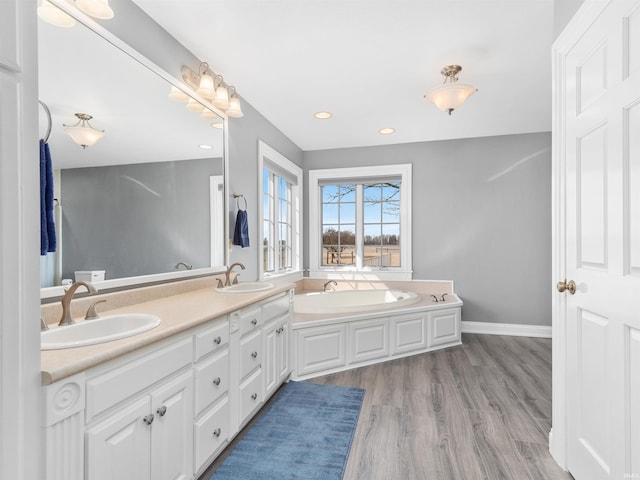 full bath featuring a sink, a garden tub, wood finished floors, and recessed lighting