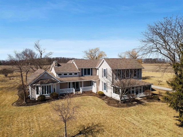 view of front of house featuring covered porch, a chimney, and a front lawn