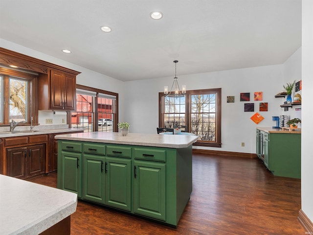 kitchen with a sink, dark wood-type flooring, a kitchen island, and light countertops