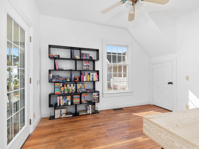 interior space featuring baseboards, visible vents, ceiling fan, hardwood / wood-style flooring, and vaulted ceiling