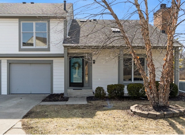 view of front of home with concrete driveway, an attached garage, and a shingled roof