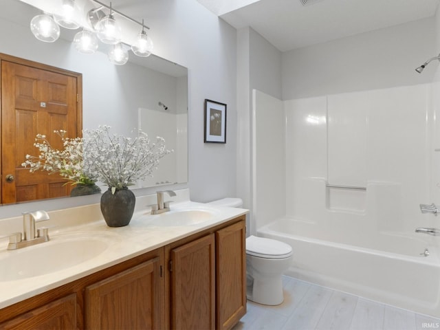 bathroom featuring double vanity, toilet, shower / tub combination, and a sink