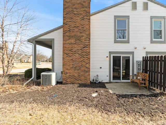 rear view of house with a patio, cooling unit, fence, and a chimney