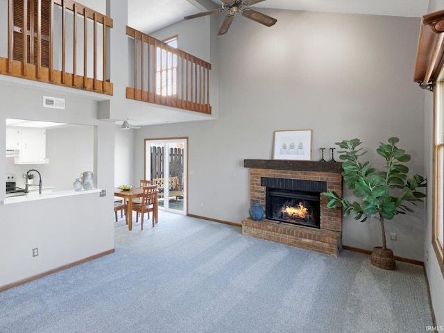 living area with a ceiling fan, visible vents, baseboards, a fireplace, and light carpet