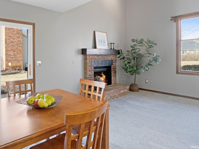 dining area with a brick fireplace, carpet flooring, and baseboards