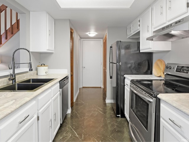 kitchen with under cabinet range hood, appliances with stainless steel finishes, white cabinetry, and a sink