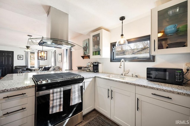 kitchen with light stone countertops, a sink, black microwave, stainless steel gas stove, and island range hood