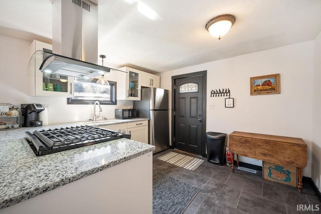 kitchen featuring freestanding refrigerator, stovetop, black microwave, island range hood, and glass insert cabinets