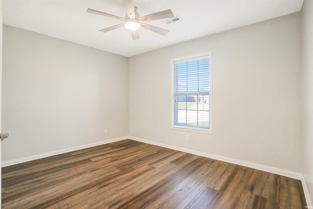 spare room with a ceiling fan, dark wood-style floors, visible vents, and baseboards